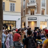 Foule animée lors d'un concert en soirée dans une rue commerçante